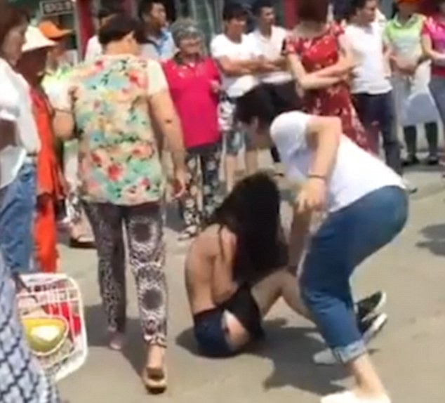 People stand by and watch the incident take place with only one woman in the flowery top trying to help