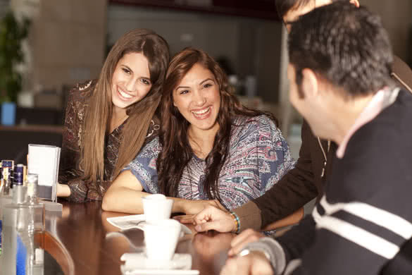 Two beautiful young women flirting with two men in the bar